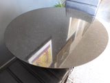 Mid-Century Modern bistro table with speckled granite top and chrome base, flanked by two black ribbed faux leather cantilever chairs on a grey carpet.
