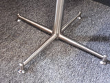 Mid-Century Modern bistro table with speckled granite top and chrome base, flanked by two black ribbed faux leather cantilever chairs on a grey carpet.