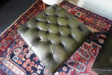 Vintage Chesterfield deep buttoned footstool in antiqued olive green leather with hardwood legs