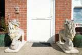 Pair of vintage weathered cast stone garden lion statues standing guard at a house entrance.