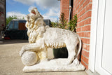 Pair of vintage weathered cast stone garden lion statues standing guard at a house entrance.