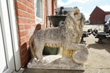 Pair of vintage weathered cast stone garden lion statues standing guard at a house entrance.