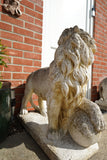 Pair of vintage weathered cast stone garden lion statues standing guard at a house entrance.
