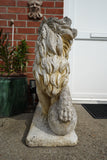 Pair of vintage weathered cast stone garden lion statues standing guard at a house entrance.