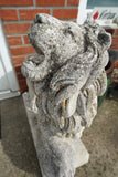 Pair of vintage weathered cast stone garden lion statues standing guard at a house entrance.