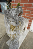 Pair of vintage weathered cast stone garden lion statues standing guard at a house entrance.