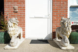 Pair of vintage weathered cast stone garden lion statues standing guard at a house entrance.
