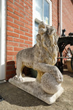 Pair of vintage weathered cast stone garden lion statues standing guard at a house entrance.
