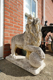 Pair of vintage weathered cast stone garden lion statues standing guard at a house entrance.