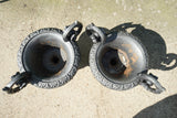 Pair of vintage black cast iron campana garden urn planters with scroll handles and flower medallions on concrete backdrop