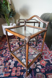Pair of vintage 1970s bamboo and glass two-tier side tables set on a patterned rug